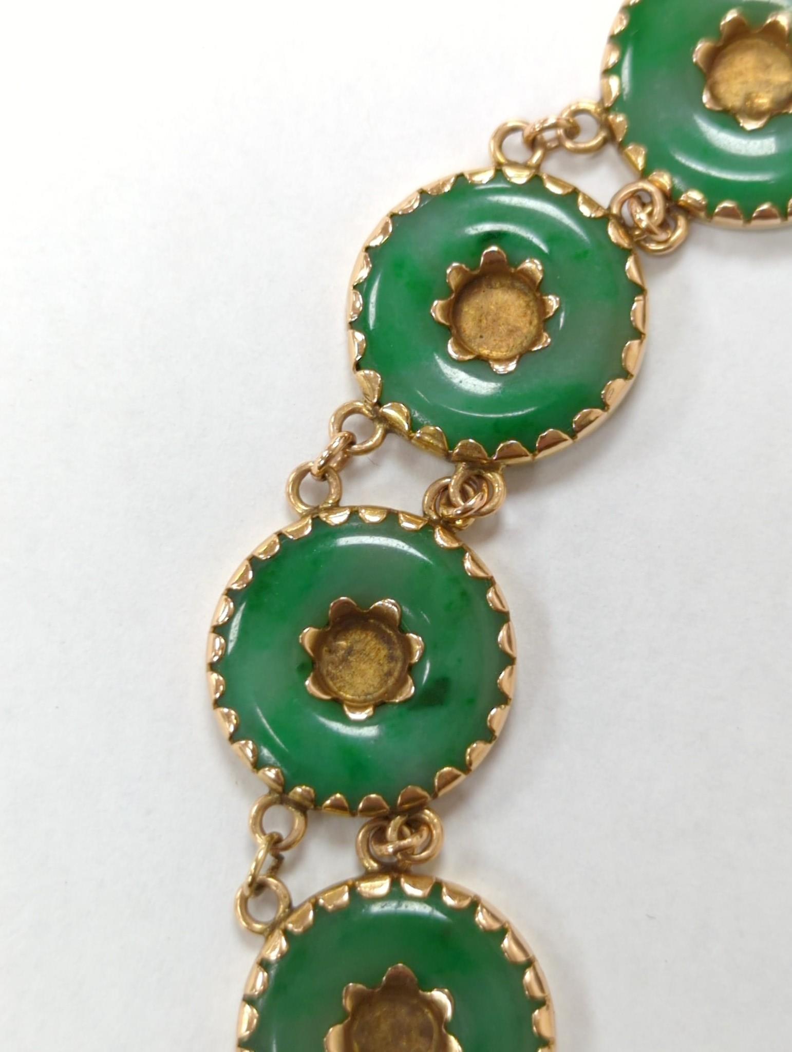 A Chinese yellow metal (stamped 18) and pierced eight stone jade disc set bracelet, with central Chinese characters, 16.5cm approx. gross weight 27.7 grams.